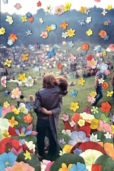 two people hugging each other in front of a field full of flowers