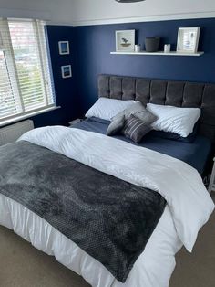 a bedroom with blue walls and white bedding