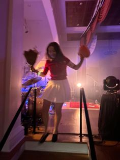 a woman in a red top and white skirt is holding a basketball while standing on some stairs