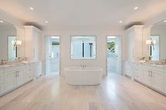 a large white bathroom with two sinks and a bathtub in the middle of it