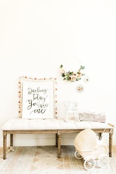 a baby's room with a white bench and flowers on the wall