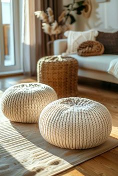 two white knitted poufles sitting on top of a rug in front of a couch