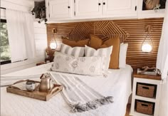 a bed with white sheets and pillows in a room next to a window that has wooden shutters