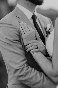 black and white photo of a bride and groom hugging each other with their hands together