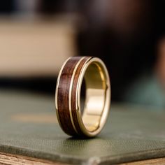 a wooden ring with gold in it sitting on top of a table next to a book