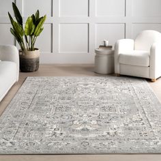 a living room with white furniture and a large rug