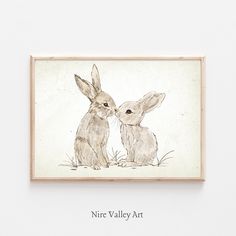 two rabbits sitting next to each other in front of a white wall with the words nire valley art on it