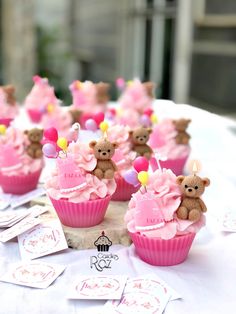 cupcakes with pink frosting and teddy bears on them are sitting on a table