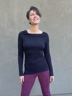 women's plant based rayon jersey long sleeve black top with slight cowl neck and side ruching #color_black Versatile Long Sleeve Ruched Top, Versatile Fitted Cowl Neck Top, Stretch Solid Color Cowl Neck Top, Fitted Long Sleeve Top With Ruched Sides, Ruched Fitted Long Sleeve Top For Fall, Stretch Ruched Tops For Fall, Fitted Tops With Ruched Sides For Fall, Versatile Black Ruched Tops, Solid Color Tops With Ruched Sides And Stretch