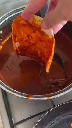 someone is dipping something into some sauce in a pan