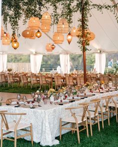 an outdoor tent with tables and chairs set up for a wedding reception in the grass