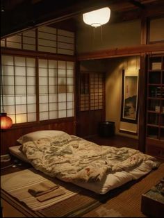 a bed sitting in the middle of a room next to a book shelf and lamp