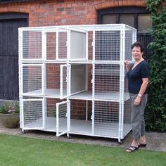 a woman standing in front of a large white caged animal house with doors open