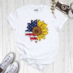 "Spread the sunshine and patriotism with our \"Sunflower Flag Shirt - USA Sunflower Flag\"! This unique and trendy shirt combines the iconic American flag with the beauty of sunflowers, creating a stunning and eye-catching design. Made with high-quality materials, this shirt is comfortable to wear and features a relaxed fit that is perfect for everyday wear. The sunflower flag design is bold and vibrant, showcasing the timeless symbol of the American flag intertwined with the cheerful and uplifting sunflowers. Our \"Sunflower Flag Shirt - USA Sunflower Flag\" is not only a fashionable choice but also a meaningful one. It's a celebration of the American spirit and the beauty of nature. It's perfect for showing your patriotism on holidays such as the 4th of July, Memorial Day, or any other d Spring Shirt With Flag Print And Short Sleeves, Spring Short Sleeve Shirt With Flag Print, Yellow Shirt With Sunflower Print For Summer, White Shirt With Flag Print For Spring, Spring White Shirt With Flag Print, White Sunflower Print Shirt For Summer, White Patriotic Shirt For Spring, Patriotic Shirt With Flag Print For Labor Day, Patriotic Flag Print Shirt For Labor Day