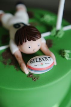 a cake decorated with a figurine laying on top of a green tablecloth