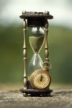 an hourglass sitting on top of a wooden table next to a small gold clock