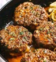 three hamburger patties in a skillet with pasta and sauce on the side, ready to be eaten