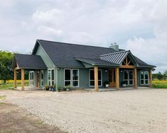 a green house with a black roof and two large windows on the front of it