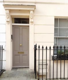 the front door of a house with wrought iron railings and a cat sitting outside