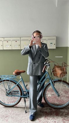 a man standing next to a blue bike holding a cell phone up to his face