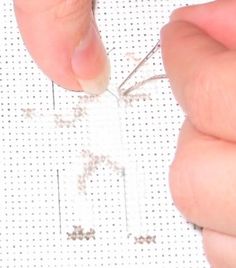 someone is working with some thread on the side of a piece of paper that has holes in it