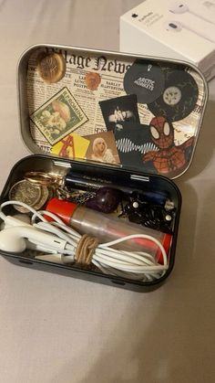 an open tin with various items in it sitting on a table next to a box