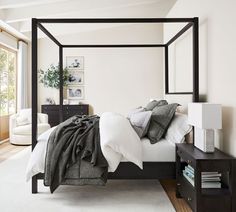 a bedroom with a four poster bed and white walls