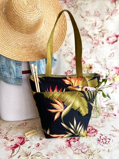 a straw hat is sitting on top of a floral print bag and next to a pair of straw hats