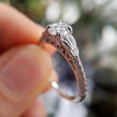 a close up of a person's hand holding a ring with a flower design on it