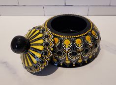 a black and yellow vase sitting on top of a white counter next to a brick wall