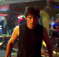 a young man is walking through a crowded bar