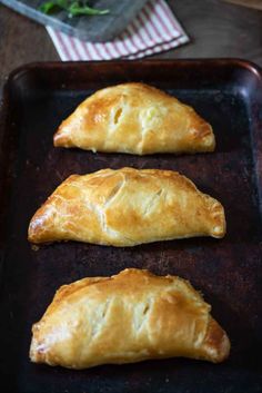 three croissants sitting on top of a baking pan