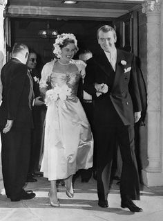 an old black and white photo of a man and woman walking out of a building