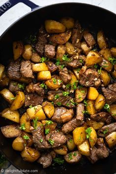 steak and potatoes in a skillet with parsley on the side, ready to be eaten