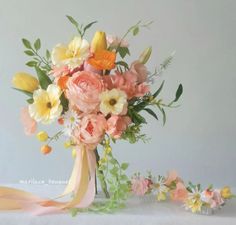 a vase filled with lots of flowers on top of a white table covered in ribbon