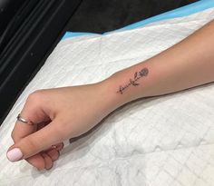 a woman's hand with a small flower tattoo on her left arm and wrist