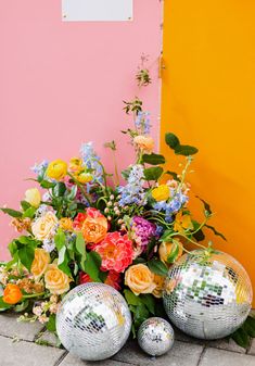 two disco ball vases sitting next to each other on a brick floor with flowers and greenery