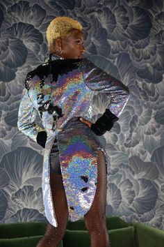 a woman is standing in front of a floral wallpaper wearing a sequin dress