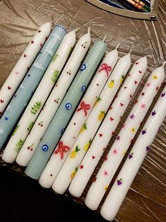 several candles are lined up on a table with plastic wrapper around them and one is empty