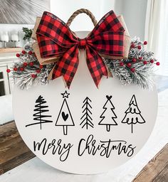 a merry christmas sign hanging on the side of a wooden table with red and black bows