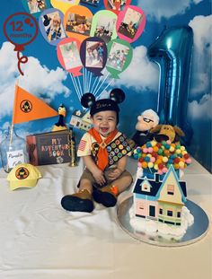 a boy sitting in front of a birthday cake with balloons and pictures on it,