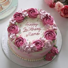 a birthday cake decorated with pink roses on a table