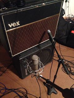 a microphone and amp sitting next to each other on the floor in front of a guitar amplifier