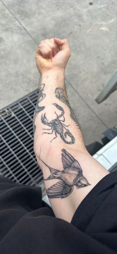 a man's arm with tattoos on it and a bird in the middle of his arm