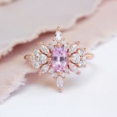 a pink diamond ring sitting on top of a piece of cloth