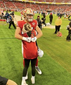 two football players hug each other on the field at a stadium as fans look on