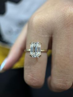 a woman's hand with a ring on her finger and an emerald stone in the middle