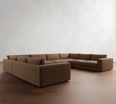 a brown sectional couch sitting on top of a wooden floor next to a white wall