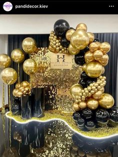 a table topped with lots of balloons and black and gold decorations on top of it