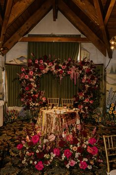 a table set up for an event with flowers on the table and chairs around it